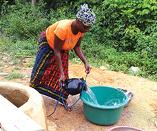 Woman pouring water into large bucket