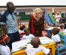 Black male and white female speaking with young children in school setting