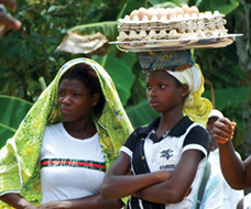 Two teenage females, one balancing a tray of eggs on her head